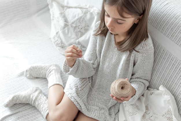 Petite fille apprenant à tricoter, concept de loisirs à la maison et de travaux d'aiguille.