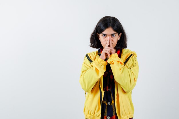 Petite fille en appuyant sur le nez avec les doigts en chemise à carreaux, veste et à la sérieuse