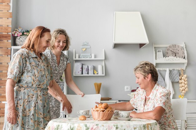 Petite fille arrangeant une chaise pour sa grand-mère dans la cuisine