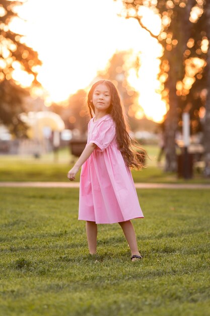 Petite fille asiatique aux cheveux longs marchant dans le parc