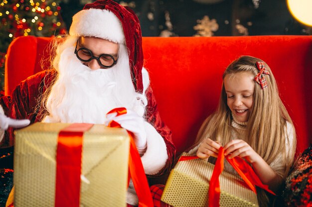 Petite fille assise avec le père Noël et des cadeaux à Noël