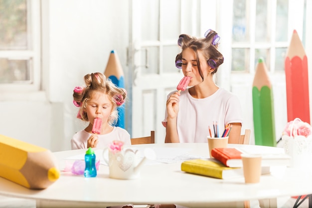 Petite fille assise avec sa mère et manger des glaces