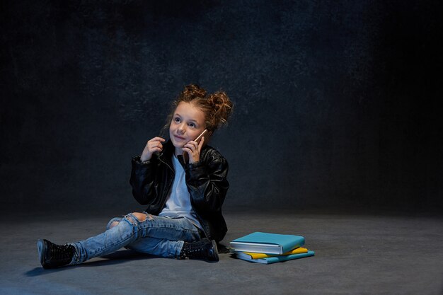 Petite fille assise avec smartphone en studio