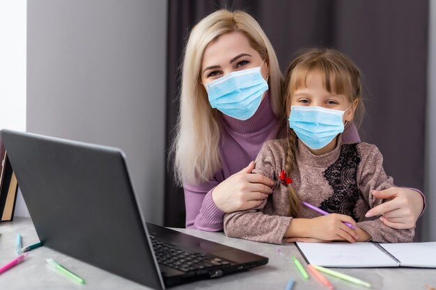 petite fille au masque médical étudiant à la maison. pandémie épidémique.