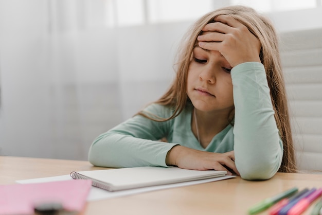 Petite fille ayant mal à la tête tout en faisant des cours en ligne