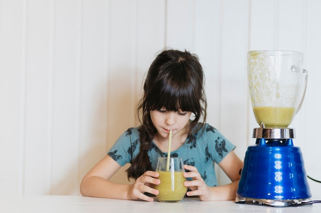 Photo gratuite petite fille ayant un smoothie au mélangeur