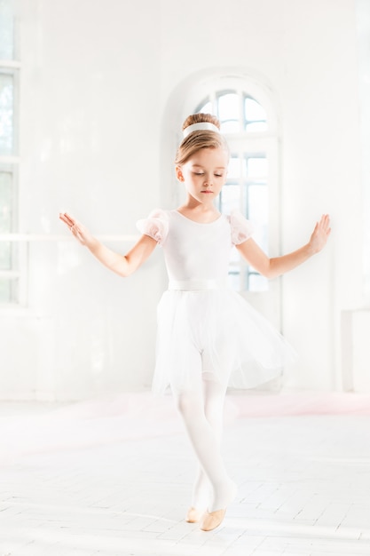 Petite fille ballerine dans un tutu. Adorable enfant dansant le ballet classique dans un studio blanc.