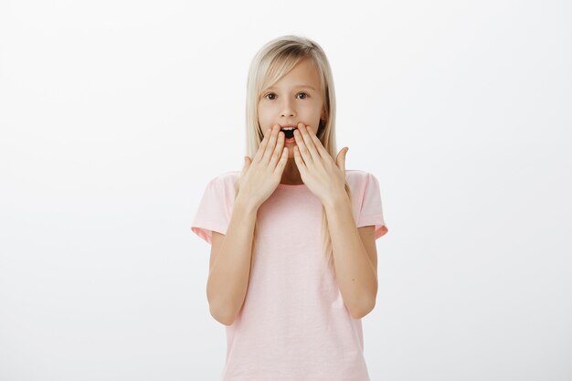 Petite fille blonde choquée et impressionnée haletante, la mâchoire tombante amusée