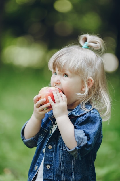 Petite fille blonde mordre une pomme