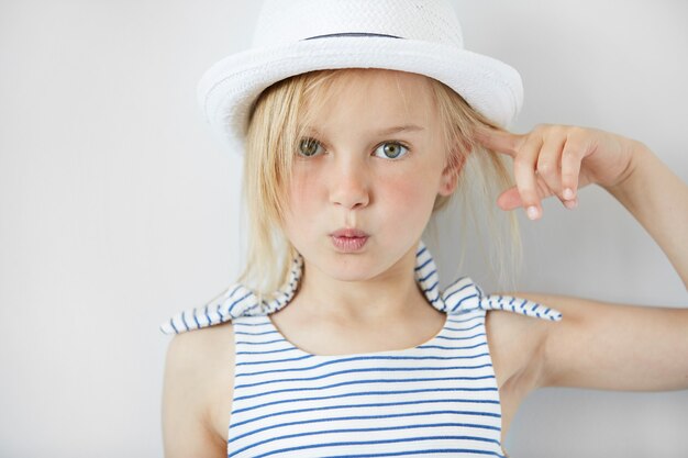 Petite fille blonde portant un chapeau blanc