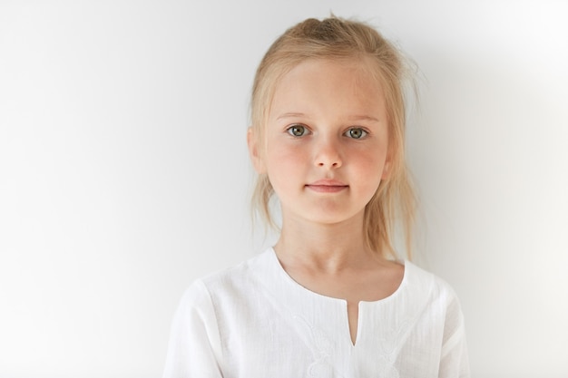 Petite fille blonde portant un chemisier blanc