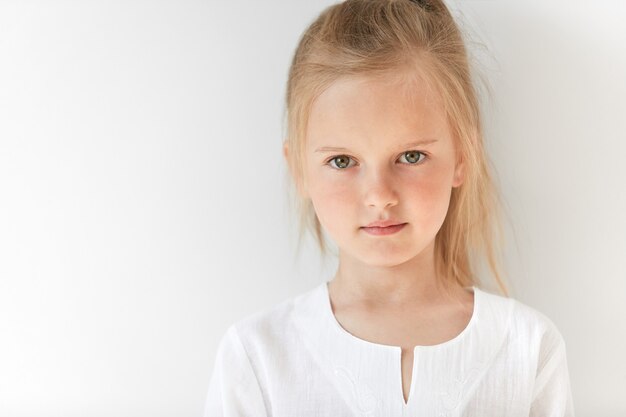 Petite fille blonde portant un chemisier blanc