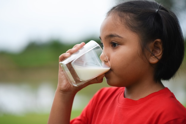 Petite fille à boire du lait dans le parc