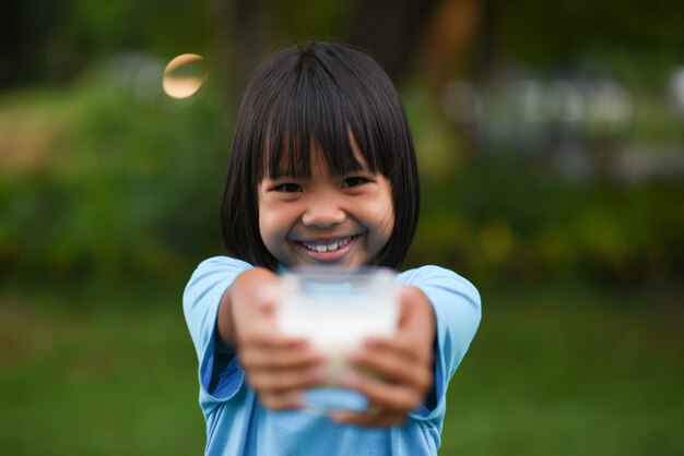 Petite fille à boire du lait dans le parc