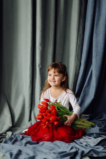 Petite fille avec bouquet de tulipes rouges