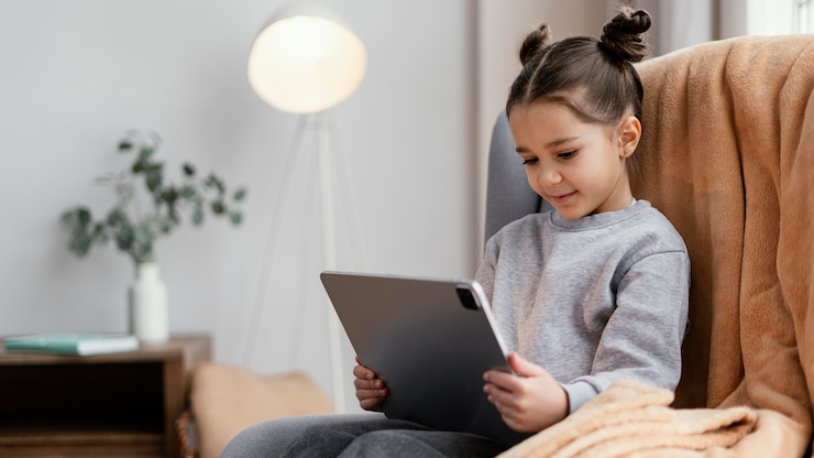 Photo gratuit petite fille sur le canapé à l'aide de tablette