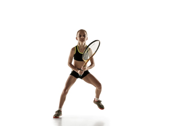 Petite fille caucasienne jouant au tennis isolé sur mur blanc