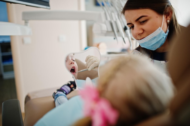 Photo gratuite petite fille à la chaise de dentiste soins dentaires pour enfants