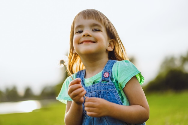 Petite fille sur un champ de pissenlit, au coucher du soleil, enfant heureux émotionnel.