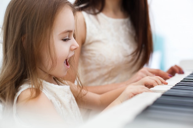 La Petite Fille Chante Alors Qu'elle Et Une Autre Femme Jouent Du Piano