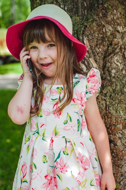 Petite fille avec chapeau rose parler au téléphone