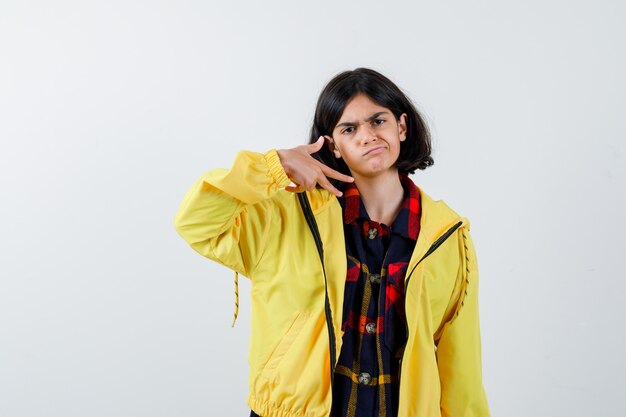 Petite fille en chemise à carreaux, veste montrant le numéro trois et à la confiance