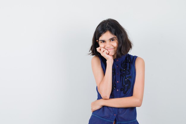 Petite fille en chemisier bleu debout dans la pensée pose et à la recherche positive