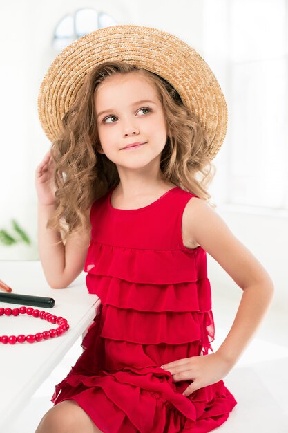 Une petite fille avec des cosmétiques assis près du miroir.