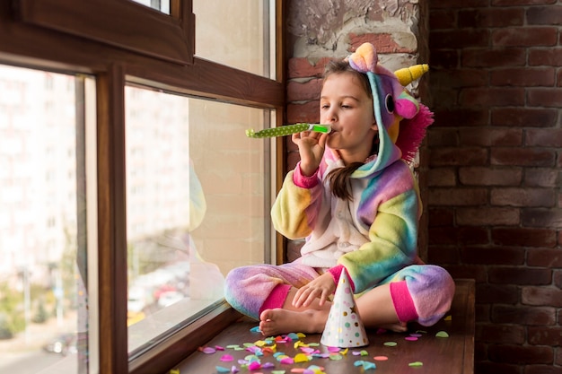 Petite fille en costume de dinosaure à la maison pendant la quarantaine