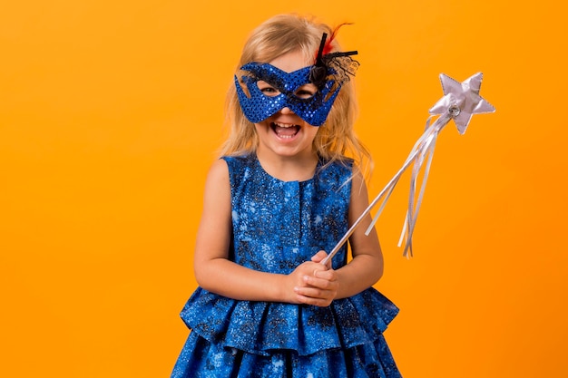 Petite fille en costume de fée avec masque et baguette