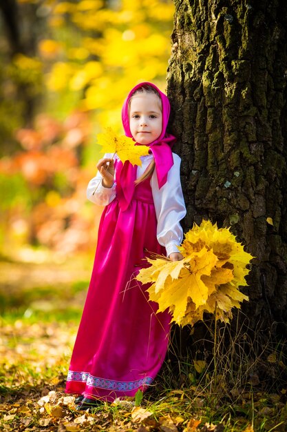 Petite fille en costumes de Masha du dessin animé Masha et ours sur la forêt d'automne