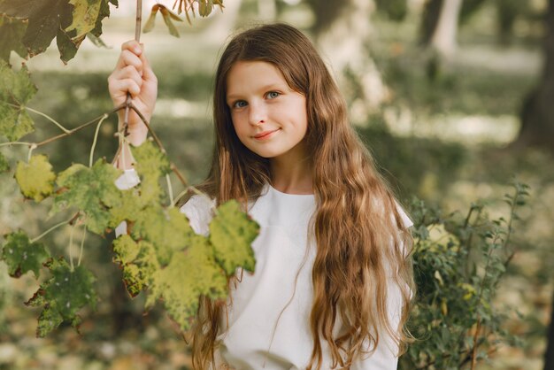 Petite fille dans un parc dans une blouse blanche