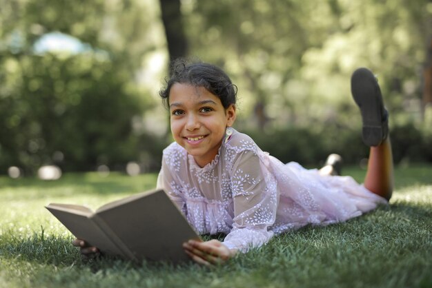 petite fille dans un parc lit un livre