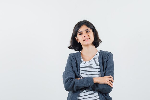 Petite fille debout avec les bras croisés en t-shirt, veste et à la fierté