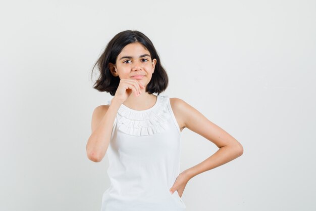 Petite fille debout dans la pensée pose en chemisier blanc et à la recherche d'espoir. vue de face.