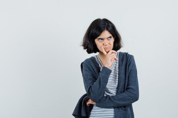 Petite fille debout dans la pensée pose en t-shirt, veste et à la sombre