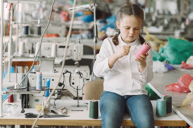 Petite fille debout dans l'usine avec un fil