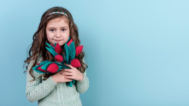 Petite fille debout avec des fleurs de jouet