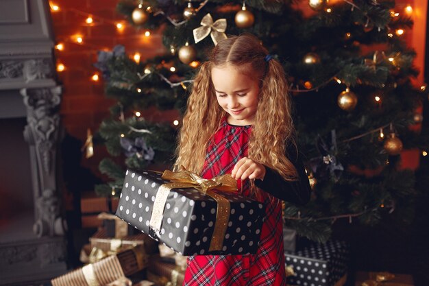 Petite fille debout près de l'arbre de Noël avec présent