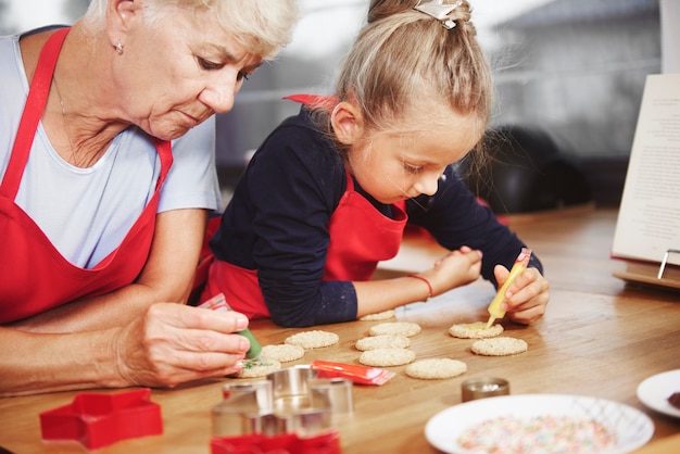 Petite fille décorant des cookies avec sa grand-mère