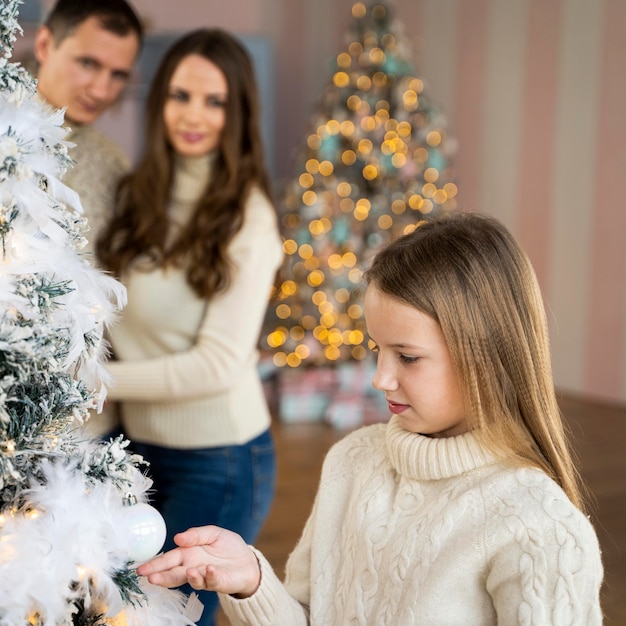 Petite fille décorant le sapin de Noël