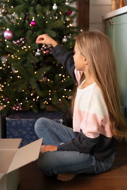 Petite fille décorant le sapin de Noël