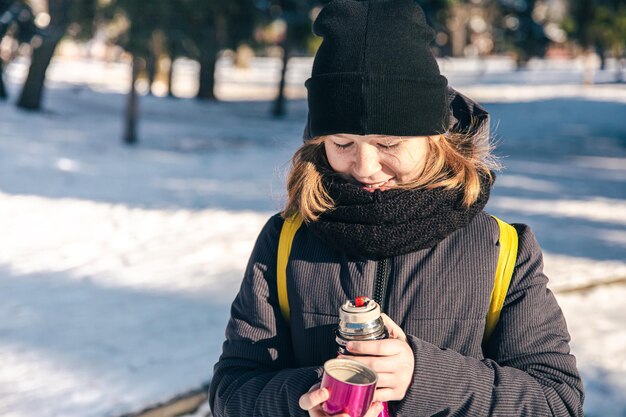 Une petite fille dehors avec un thermos par une froide journée d'hiver