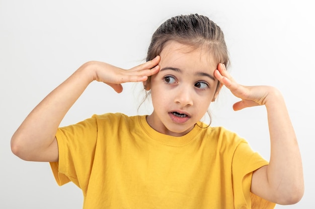 Photo gratuite une petite fille désespérée qui a l'air paniquée tenant sa tête avec ses deux mains.