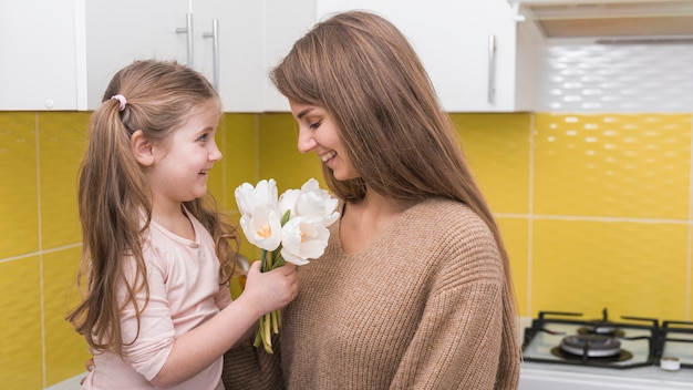 Photo gratuite petite fille donnant des tulipes à sa mère