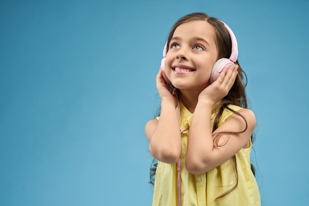 Petite fille, écouter de la musique dans les écouteurs roses.