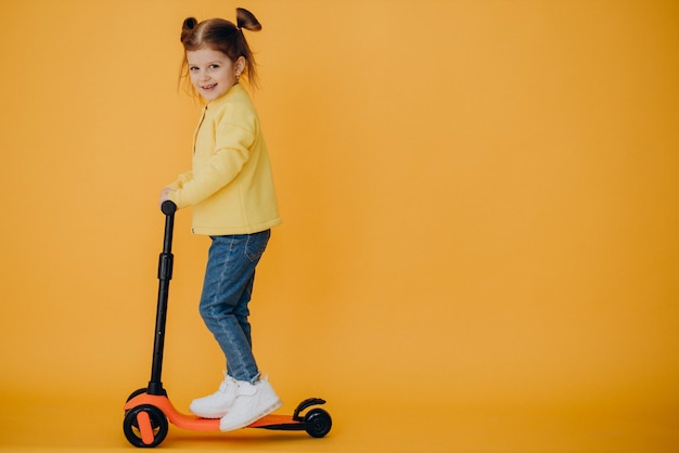 Photo gratuite petite fille faisant du scooter en studio