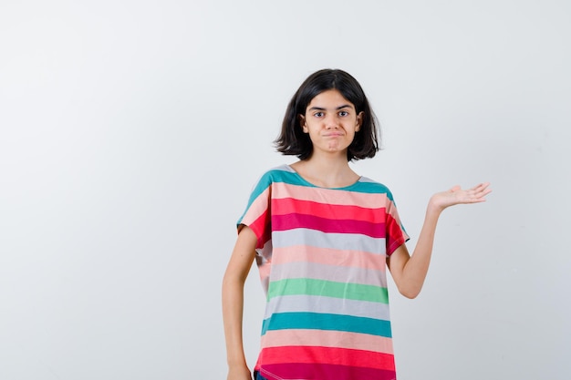 Petite fille faisant un geste de bienvenue en t-shirt et ayant l'air confiant. vue de face.