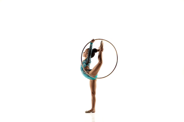 Petite fille flexible isolée sur blanc. Petit modèle féminin en tant qu'artiste de gymnastique rythmique en justaucorps brillant.