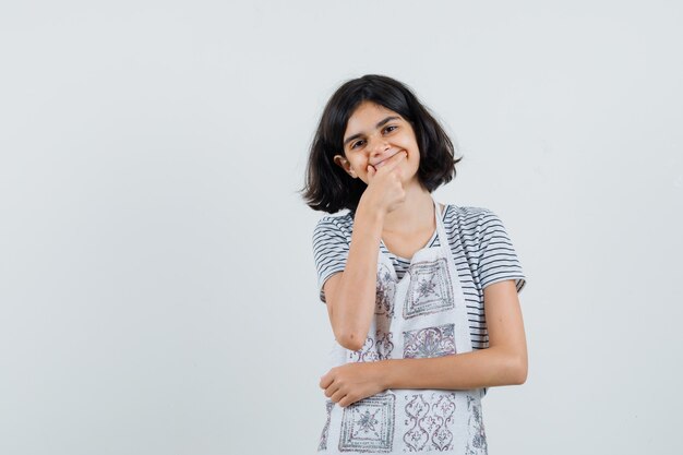 Petite fille forçant un sourire sur le visage en t-shirt, tablier